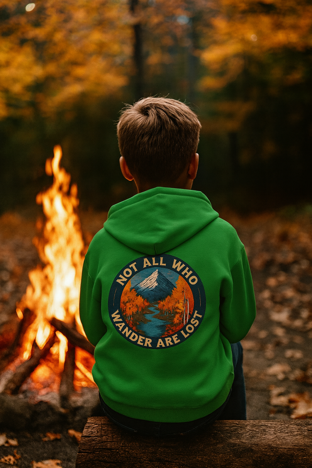 Person wearing a green hoodie with a nature-themed design by a campfire in a forest setting